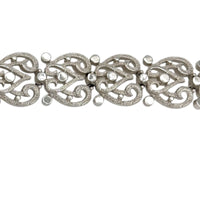 Close up view of the links of Trifari silver-tone vintage bracelet featuring filigree scroll links and beaded accents on white background.