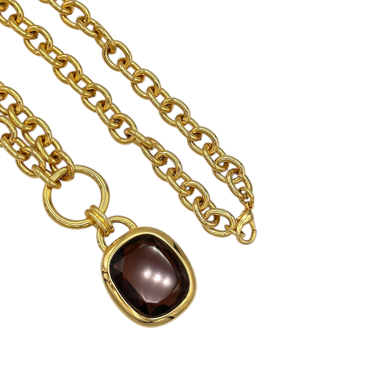 Close up of pendant of Vintage Joan Rivers gold link necklace with smoky brown topaz glass pendant displayed on white background.