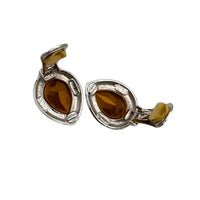 Clips open of Vintage Kenneth Jay Lane clear teardrop rhinestone clip-on earrings with black enamel border displayed on white background.