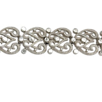 Close up view of the links of Trifari silver-tone vintage bracelet featuring filigree scroll links and beaded accents on white background.
