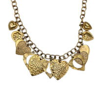 close up of charms of Vintage gold heart charm necklace with textured hearts and link chain displayed on white background.