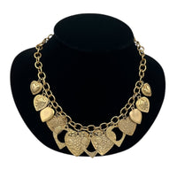 Close up view of Vintage gold heart charm necklace with textured hearts and link chain displayed on black velvet bust.