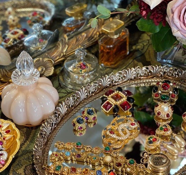 Vintage brooches on mirrored vanity tray with feminine details.