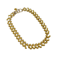 Close up view of Anne Klein II vintage gold link statement necklace on display on white background.