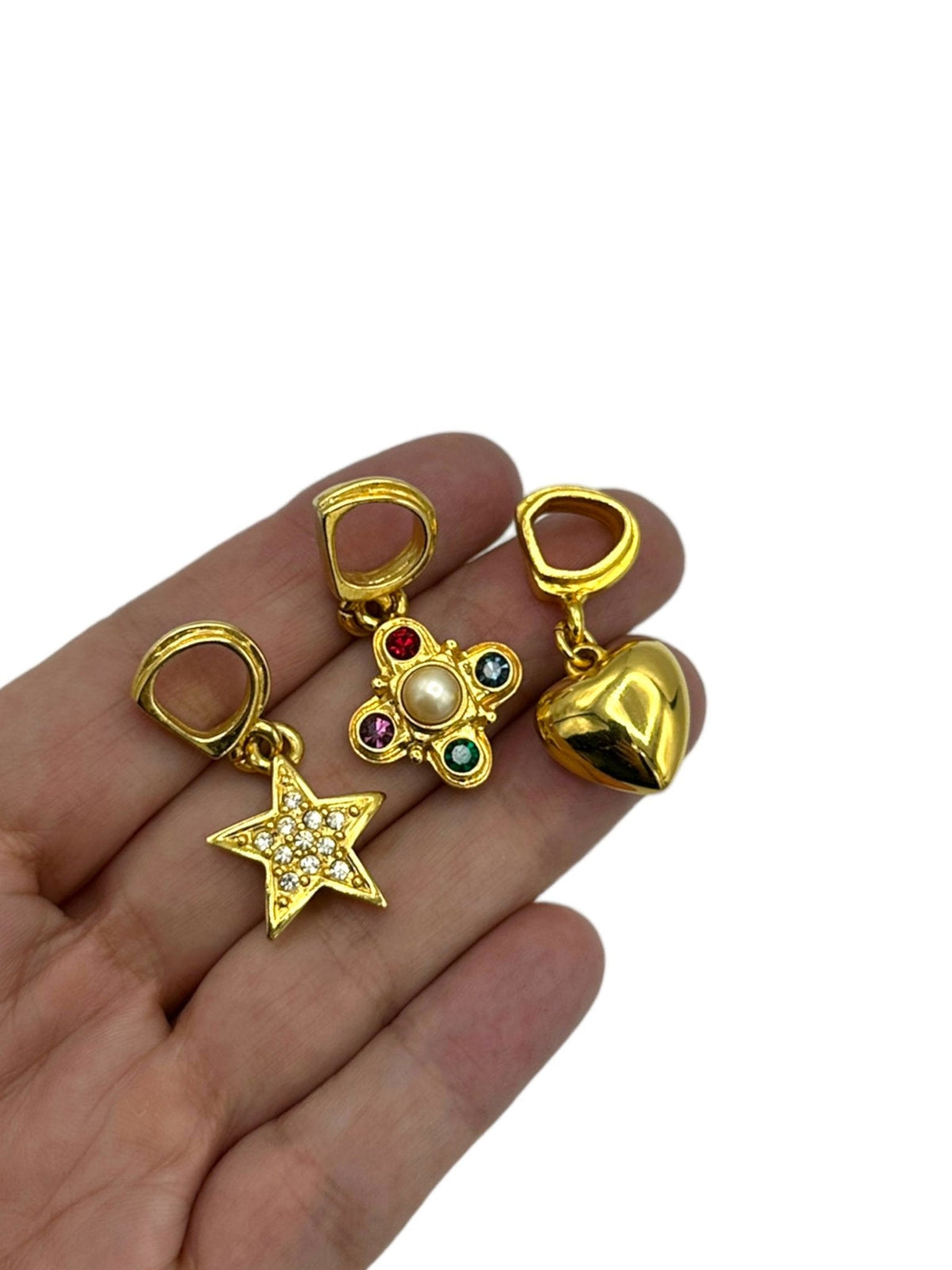 Set of three vintage Carolee slide charms including gold heart, rhinestone star, and pearl with colorful gems, shown on hand.