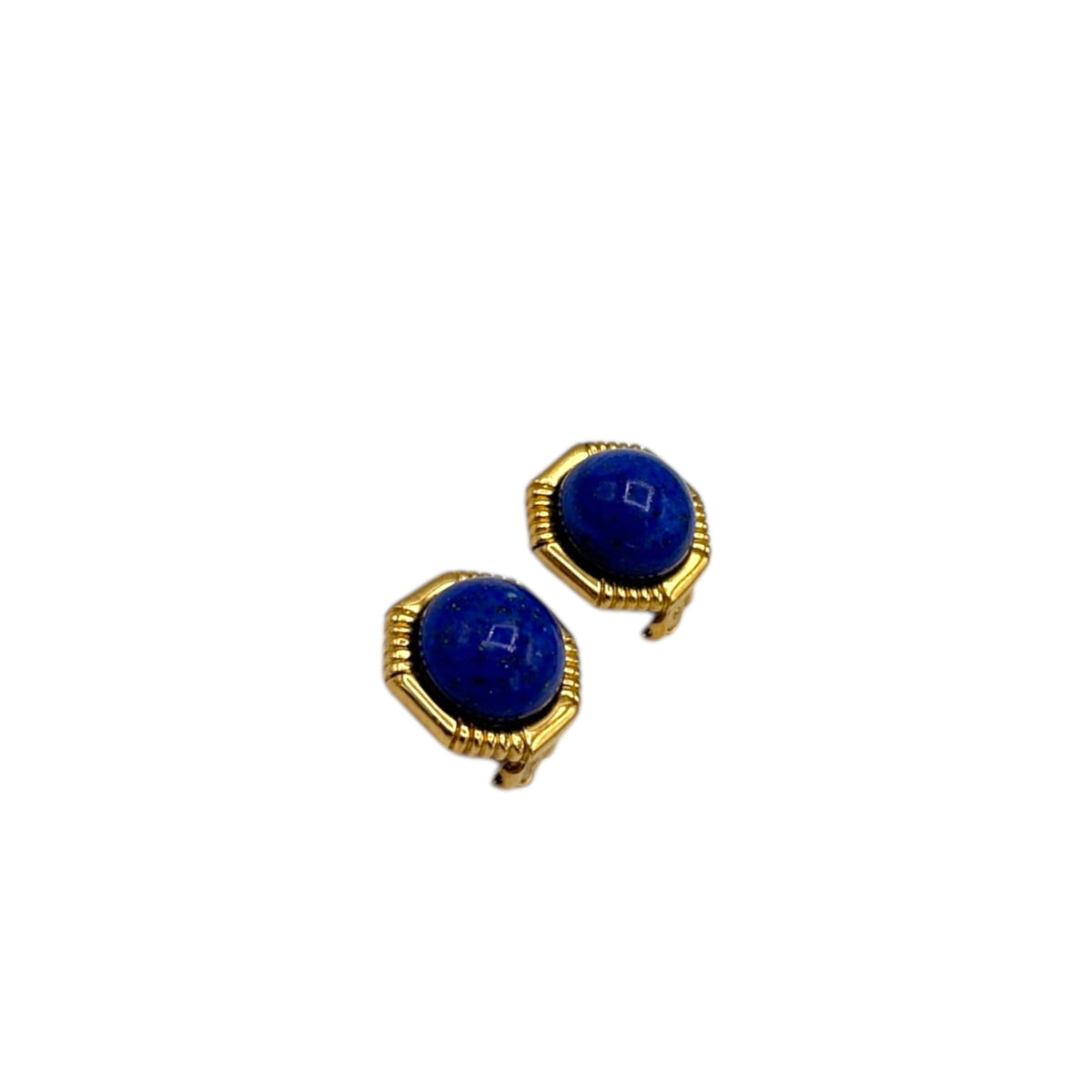 Side view of Vintage Ciner gold clip-on earrings with round blue lapis glass cabochons displayed on white background.