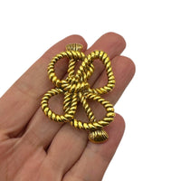 Shown on hand to show size, MMA vintage gold rope bow brooch with textured loops on white background.