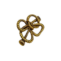 Side view of MMA vintage gold rope bow brooch with textured loops on white background.