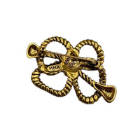 Back view of MMA vintage gold rope bow brooch with textured loops on white background.