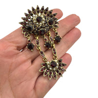 Shown on hand to show size, Hollycraft Victorian Revival brooch with deep red rhinestones, faux pearls, and cascading gold-tone dangles – vintage statement jewelry shown on white background.