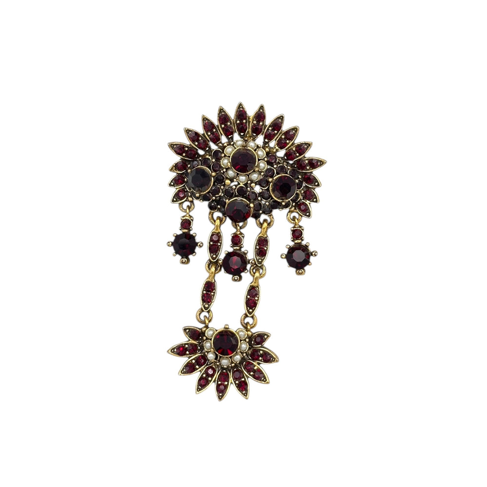 Close up view of Hollycraft Victorian Revival brooch with deep red rhinestones, faux pearls, and cascading gold-tone dangles – vintage statement jewelry shown on white background.