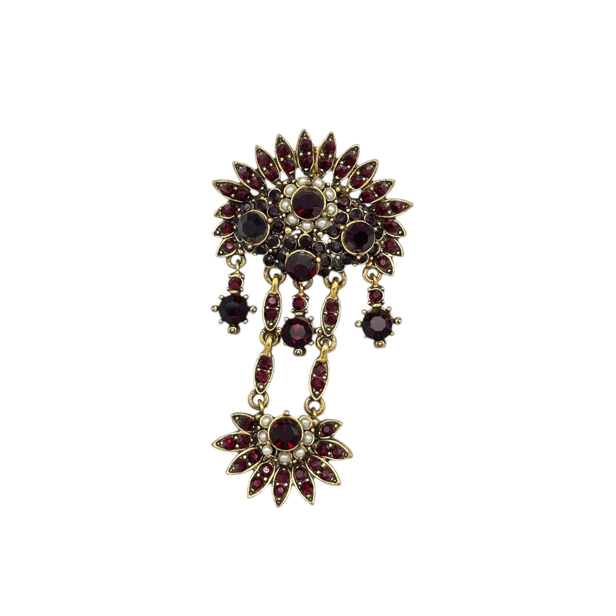 Close up view of Hollycraft Victorian Revival brooch with deep red rhinestones, faux pearls, and cascading gold-tone dangles – vintage statement jewelry shown on white background.