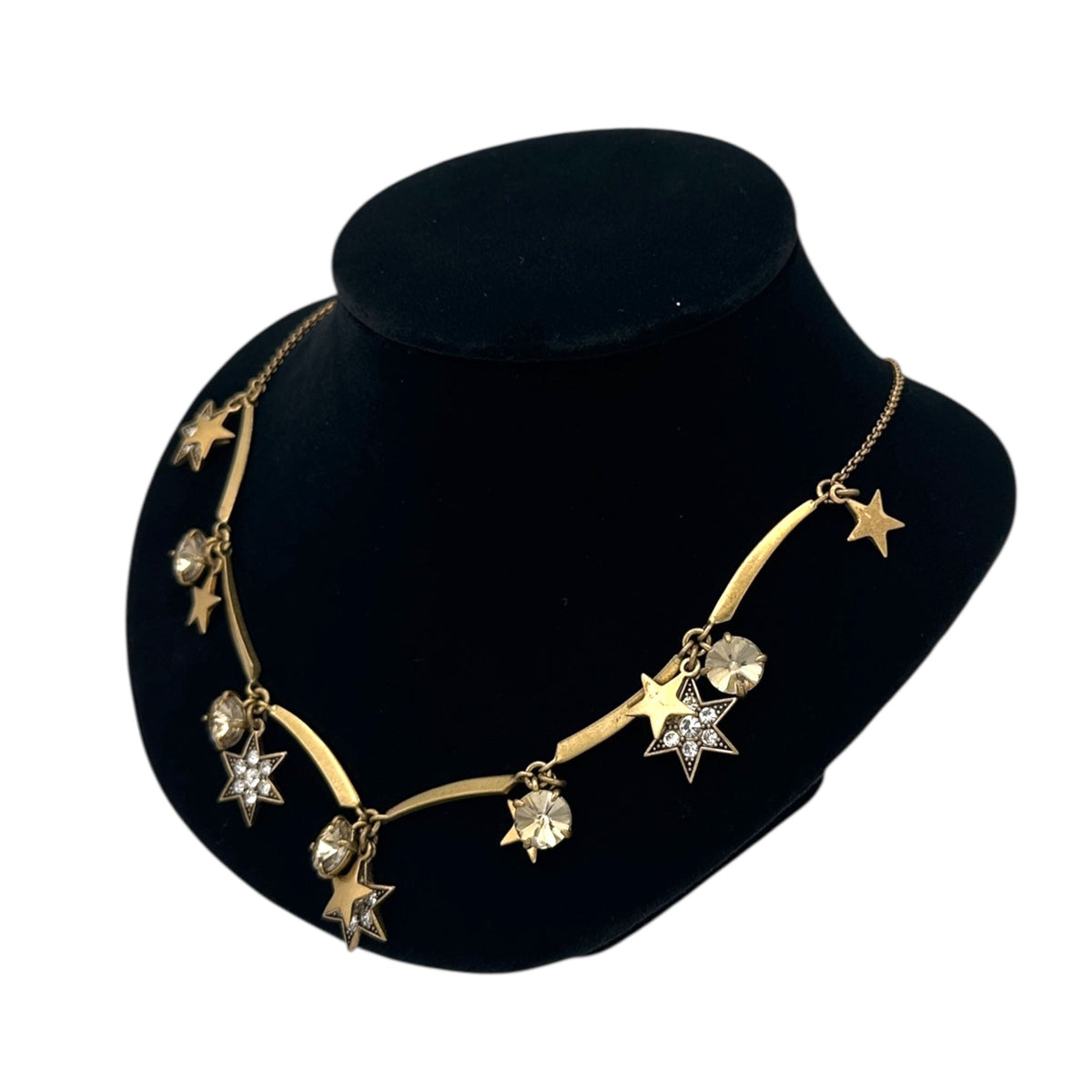 Side view of J. Crew vintage antiqued gold star charm necklace with rhinestone accents displayed on a black jewelry bust.