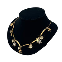 Side view of J. Crew vintage antiqued gold star charm necklace with rhinestone accents displayed on a black jewelry bust.