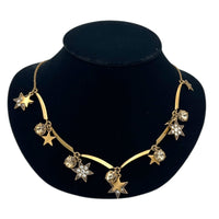 Close up view of J. Crew vintage antiqued gold star charm necklace with rhinestone accents displayed on a black jewelry bust.