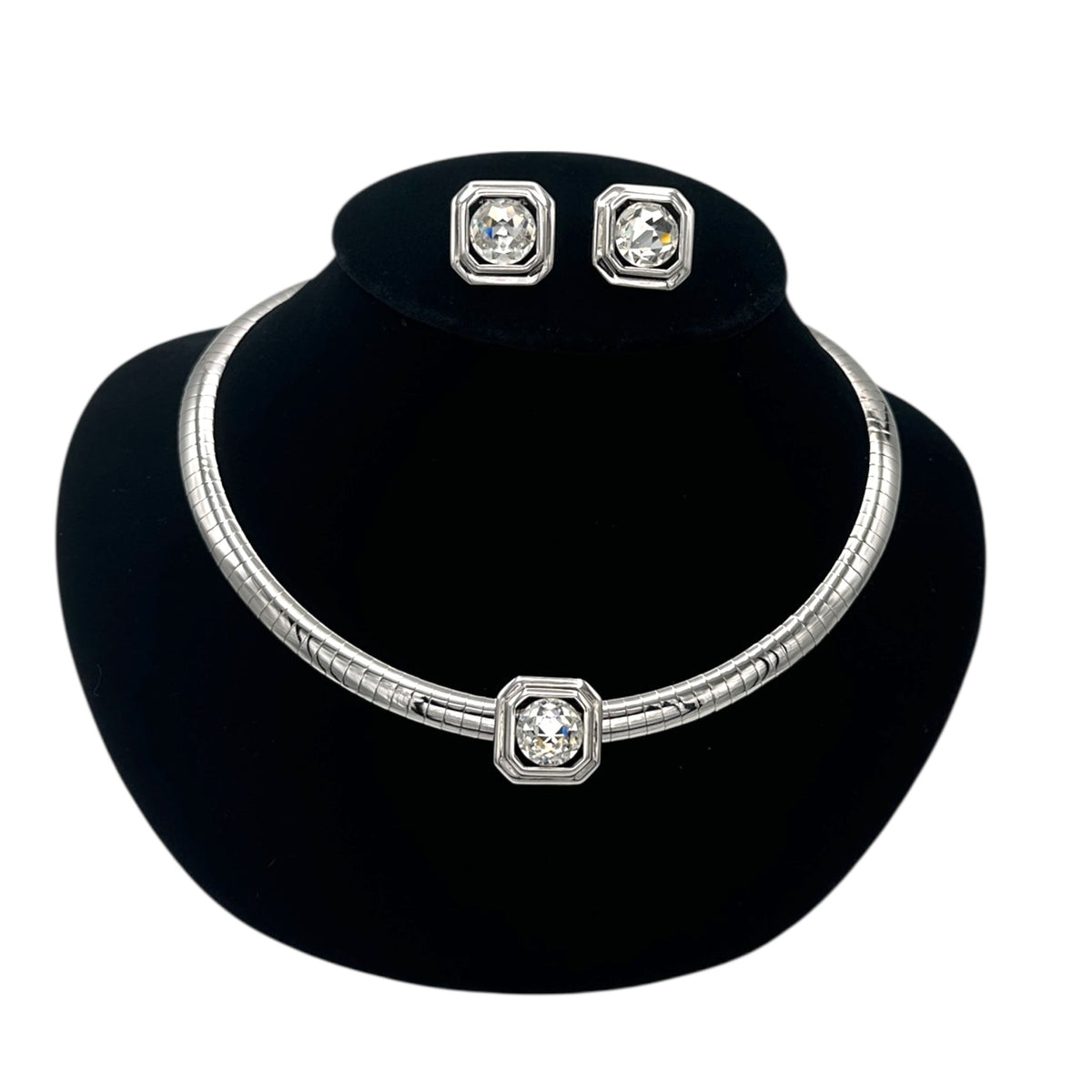 Close up view of Vintage Joan Rivers silver omega necklace and matching clear rhinestone clip-on earring set on black bust.