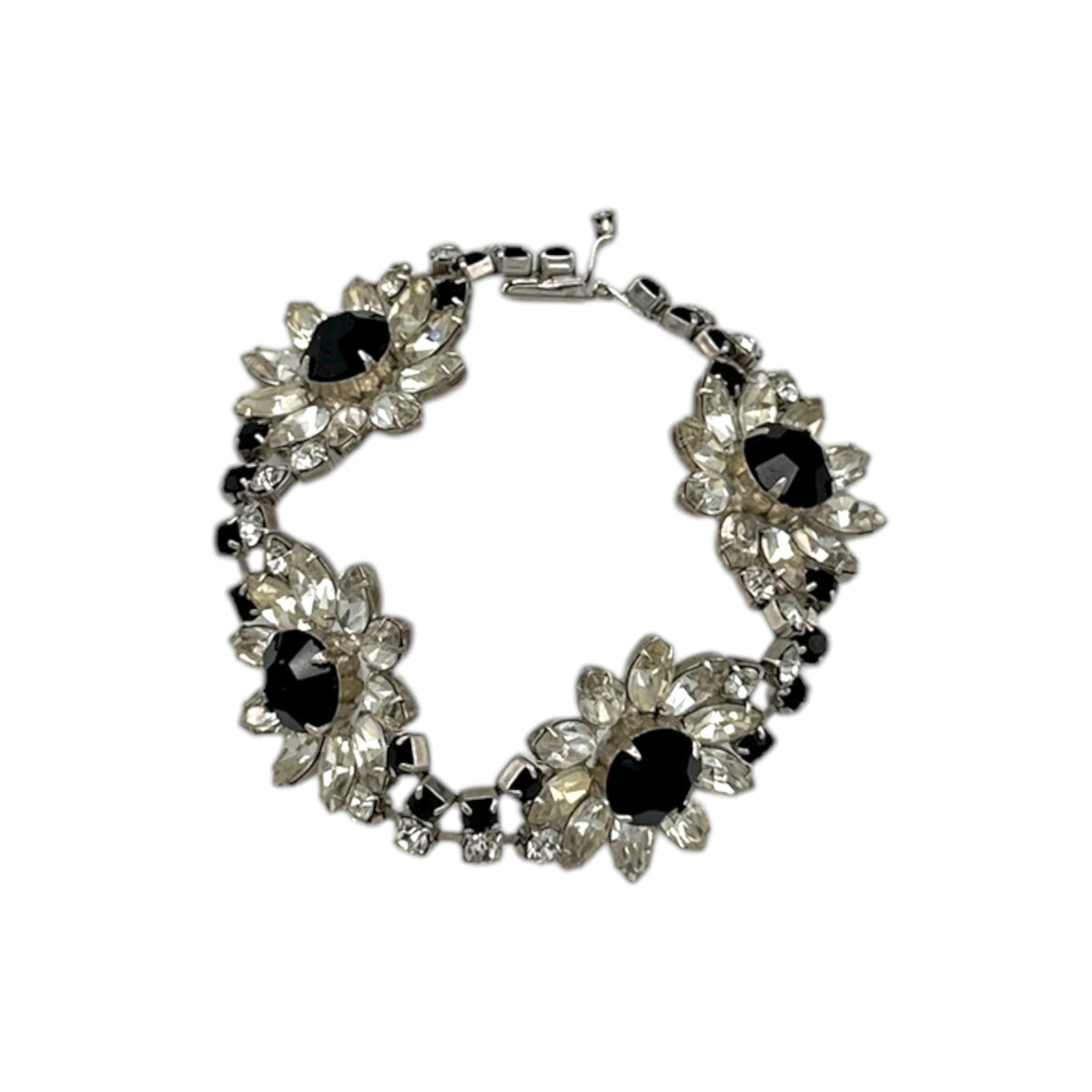 Close up view of Kirks Folly vintage bracelet with clear and black rhinestone flower design on white background.