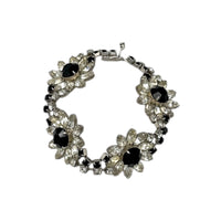 Close up view of Kirks Folly vintage bracelet with clear and black rhinestone flower design on white background.