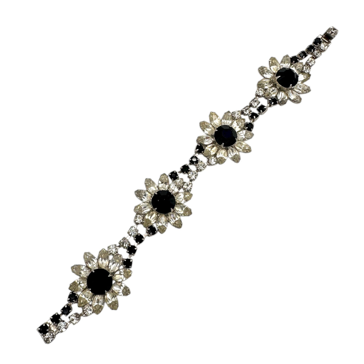 Laying flat close up view of Kirks Folly vintage bracelet with clear and black rhinestone flower design on white background.