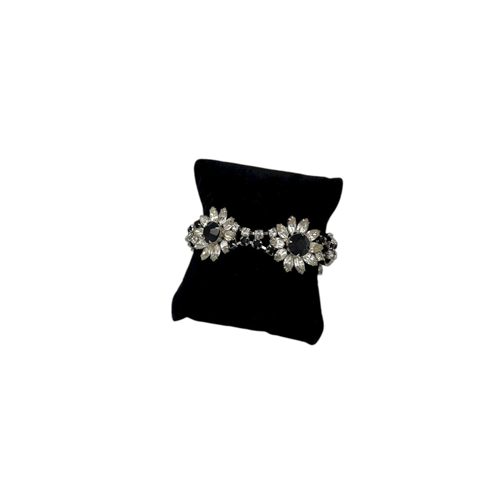 Kirks Folly vintage bracelet with clear and black rhinestone flower design on back pillow and white background.