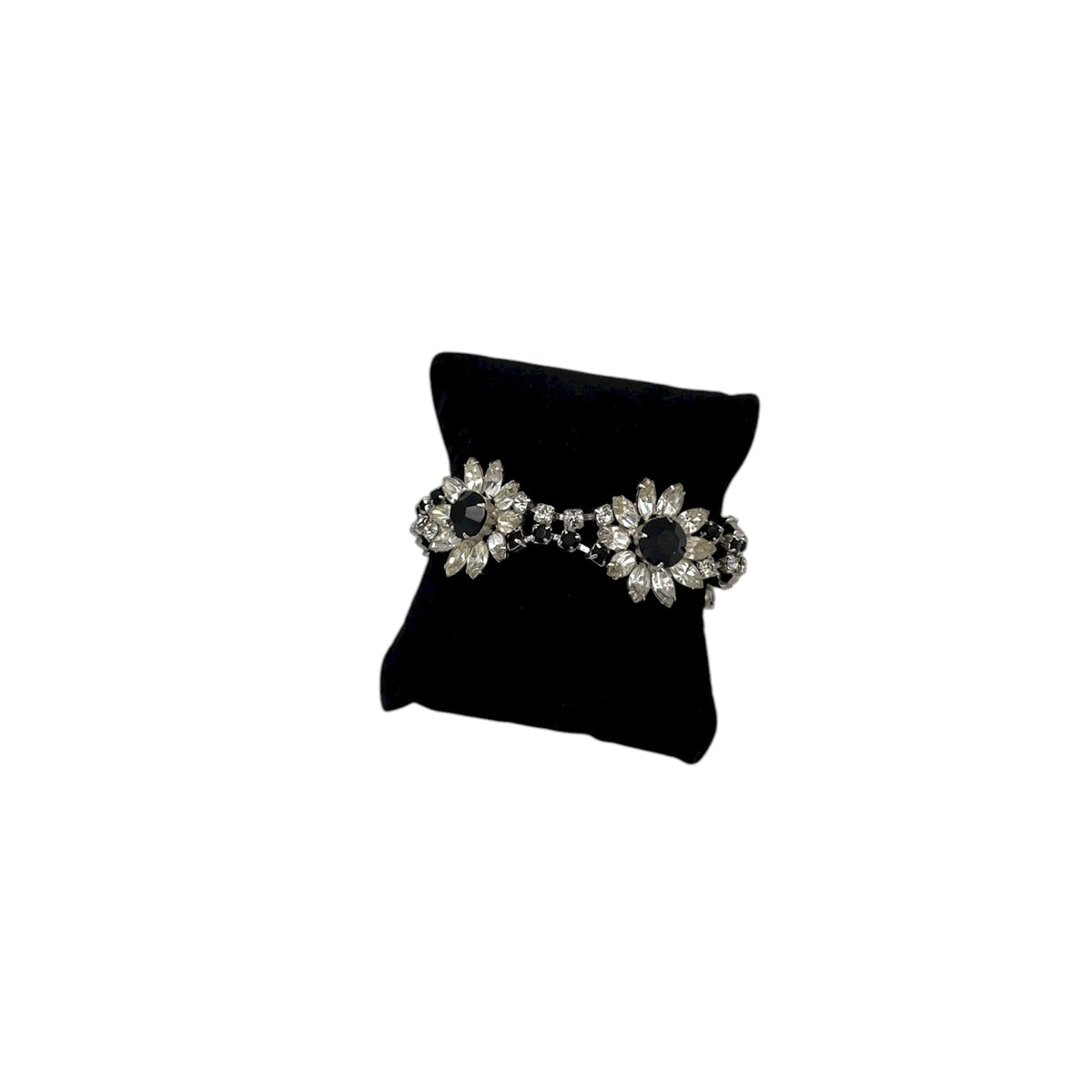 Kirks Folly vintage bracelet with clear and black rhinestone flower design on back pillow and white background.
