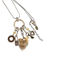 Back of pendant of Vintage Liz Palacios San Francisco silver charm necklace with heart and key pendants displayed on white background.