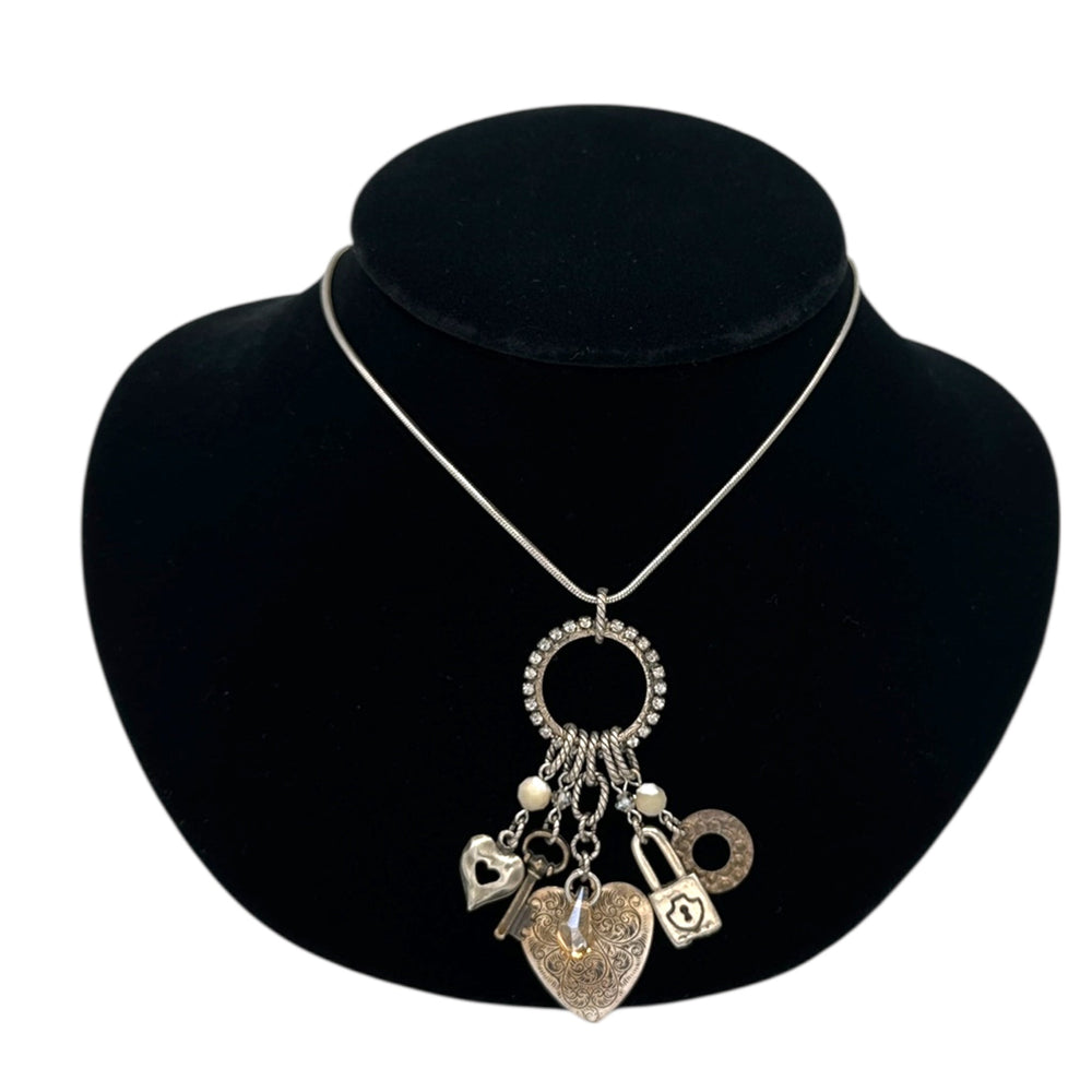 Close up view of Vintage Liz Palacios San Francisco silver charm necklace with heart and key pendants displayed on black velvet bust.