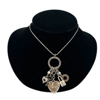 Close up view of Vintage Liz Palacios San Francisco silver charm necklace with heart and key pendants displayed on black velvet bust.