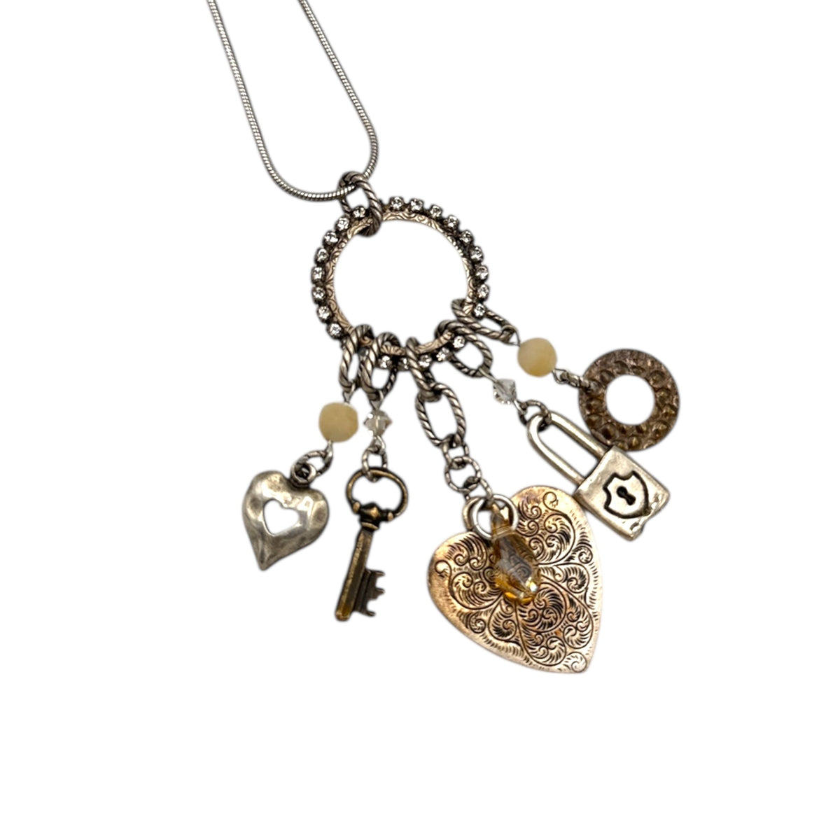 Close up of charms of Vintage Liz Palacios San Francisco silver charm necklace with heart and key pendants displayed on white background.