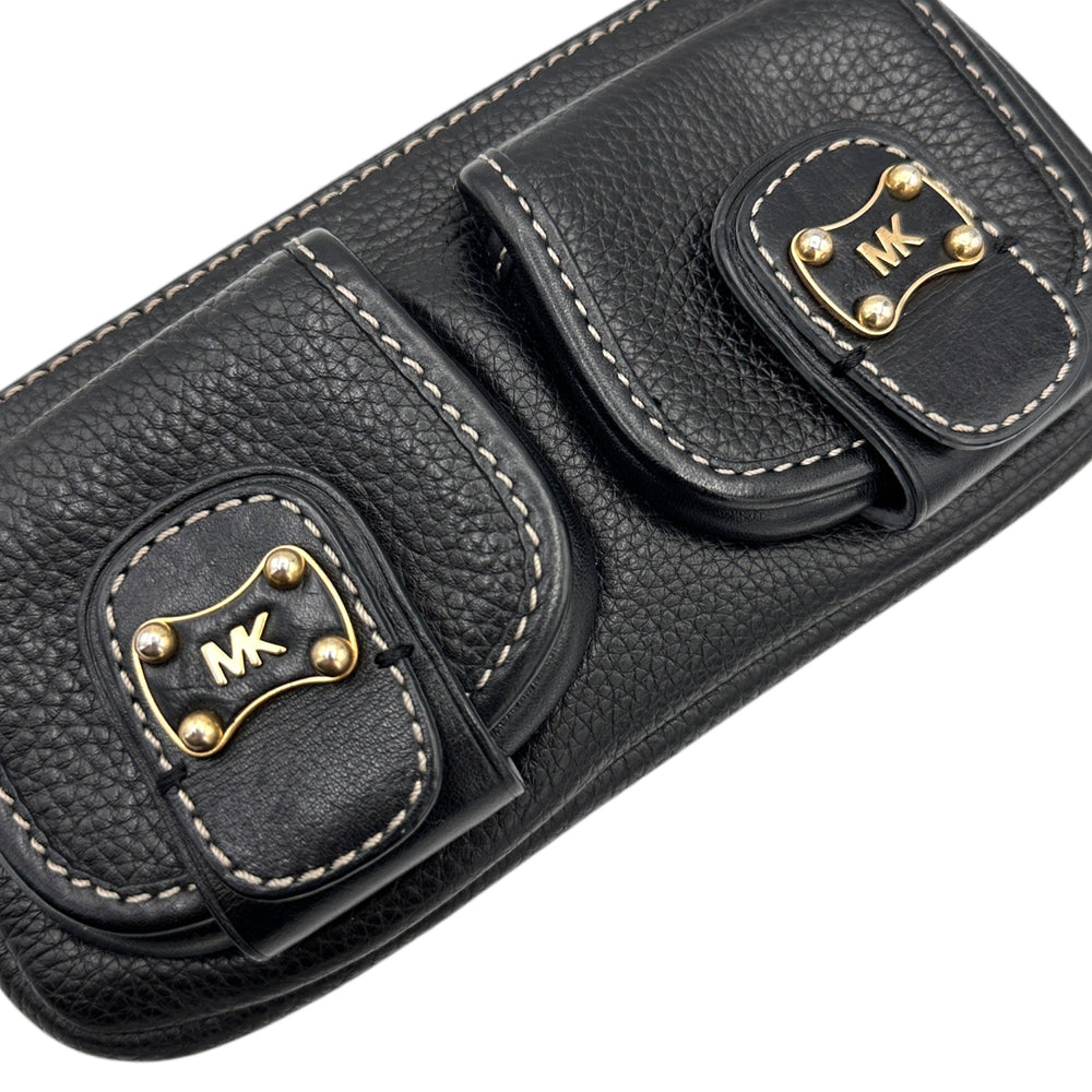 Close up of front pockets of Vintage Michael Kors black pebbled leather Roadie bag with gold hardware and dual front pockets displayed on white background.