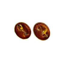 Back view of Monet vintage gold oval clip-on earrings with opalescent cabochon centers and textured gold frame on white background.