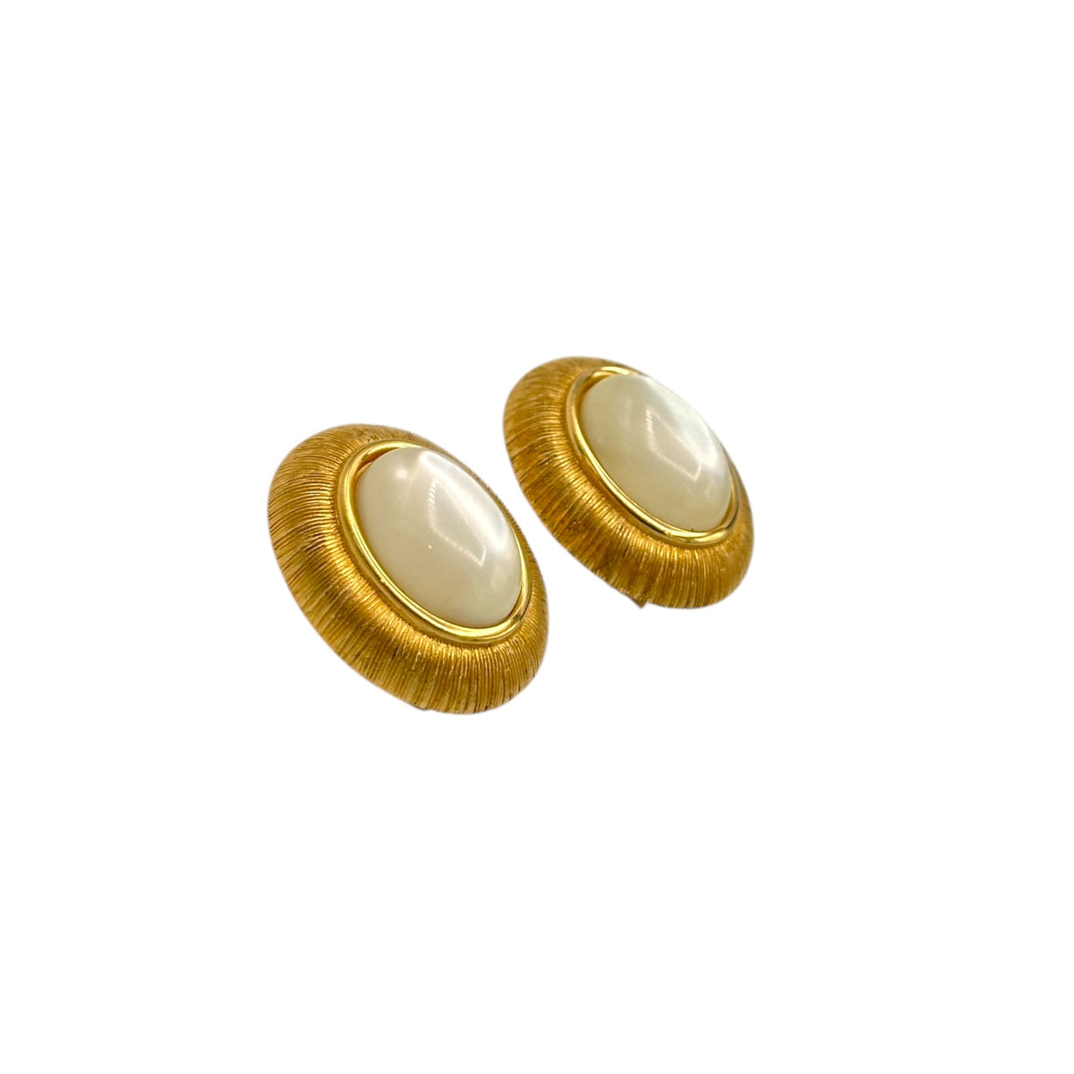 Side view of Monet vintage gold oval clip-on earrings with opalescent cabochon centers and textured gold frame on white background.
