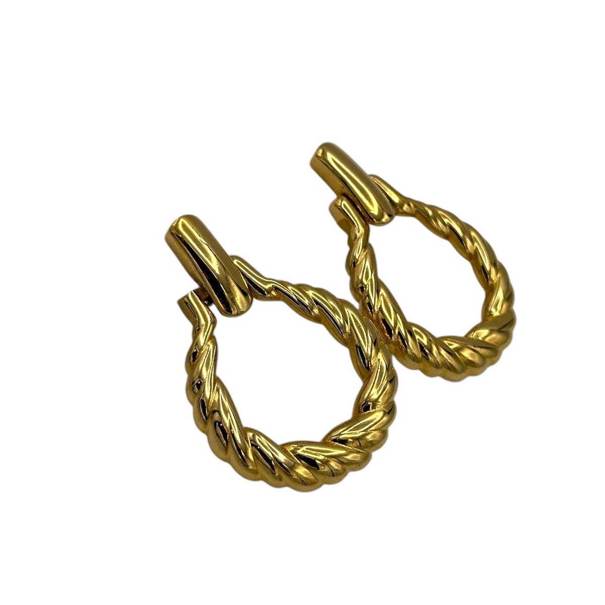 Close up side view of Monet vintage gold twisted swirl doorknocker clip-on earrings displayed on white background.