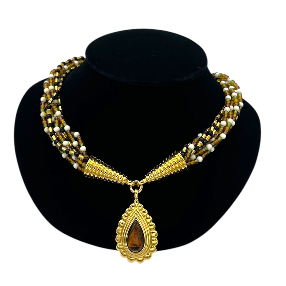 Close up view of Monet vintage gold multi-strand beaded necklace with a brown teardrop pendant and gold accents on a black bust with white background.