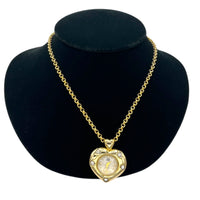 Close up view of Vintage Nolan Miller gold heart pendant watch with rhinestone accents on long cable chain displayed on black velvet bust.