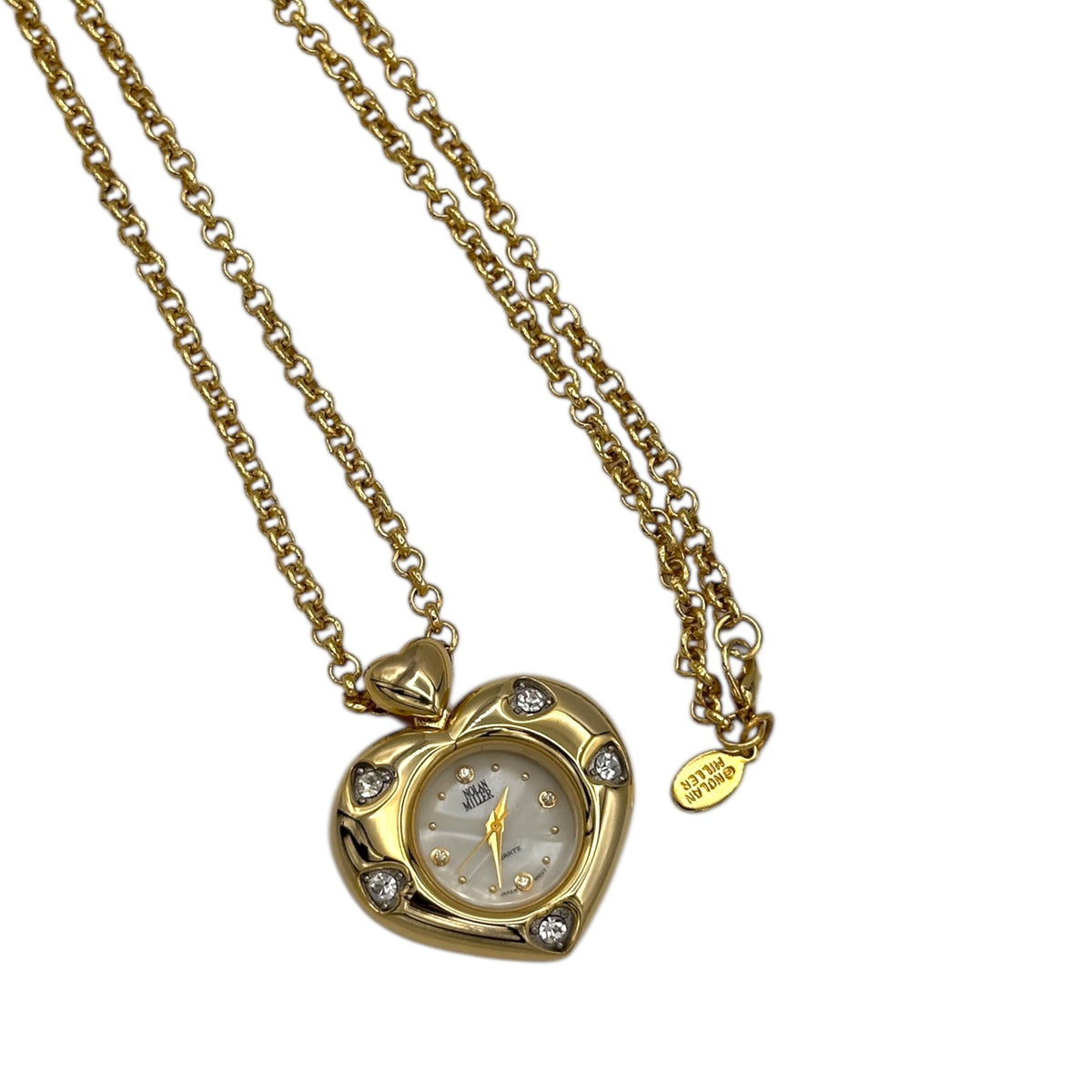 Close up of watch pendant of Vintage Nolan Miller gold heart pendant watch with rhinestone accents on long cable chain displayed on white background.