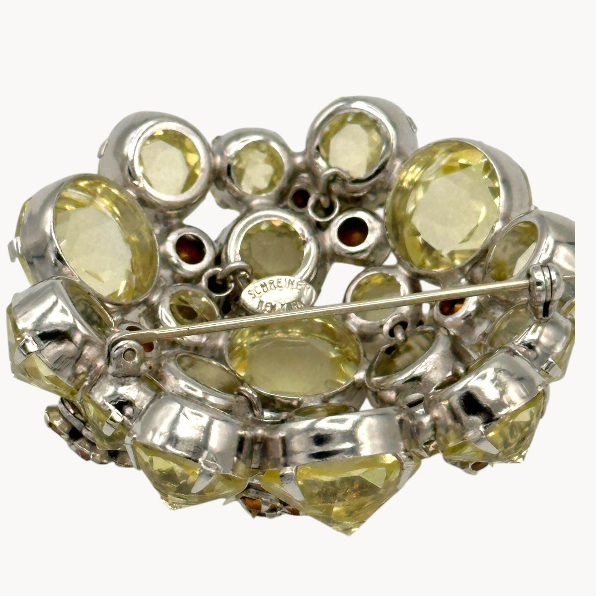 Close up view of back of Schreiner brooch with the signature on white background.