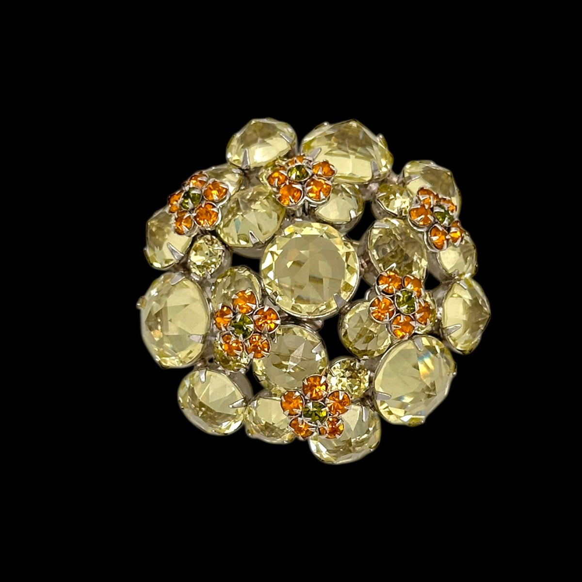 Top view of Schreiner brooch on black background.