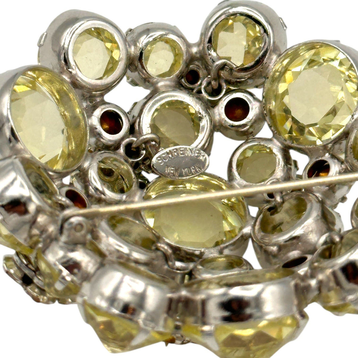 Close up view of back of Schreiner brooch on white background. 