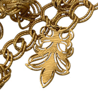 Close up of back view of dangle of Vintage St. John matte gold layered bib belt with ornate leaf accents and curb chain design displayed on white background.