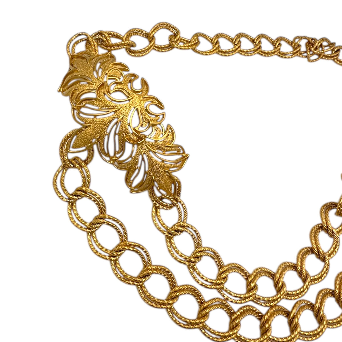 Left side view of Vintage St. John matte gold layered bib belt with ornate leaf accents and curb chain design displayed on white background.