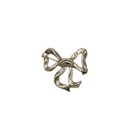 Vintage sterling silver bow brooch with polished ribbon design, photographed on white background.
