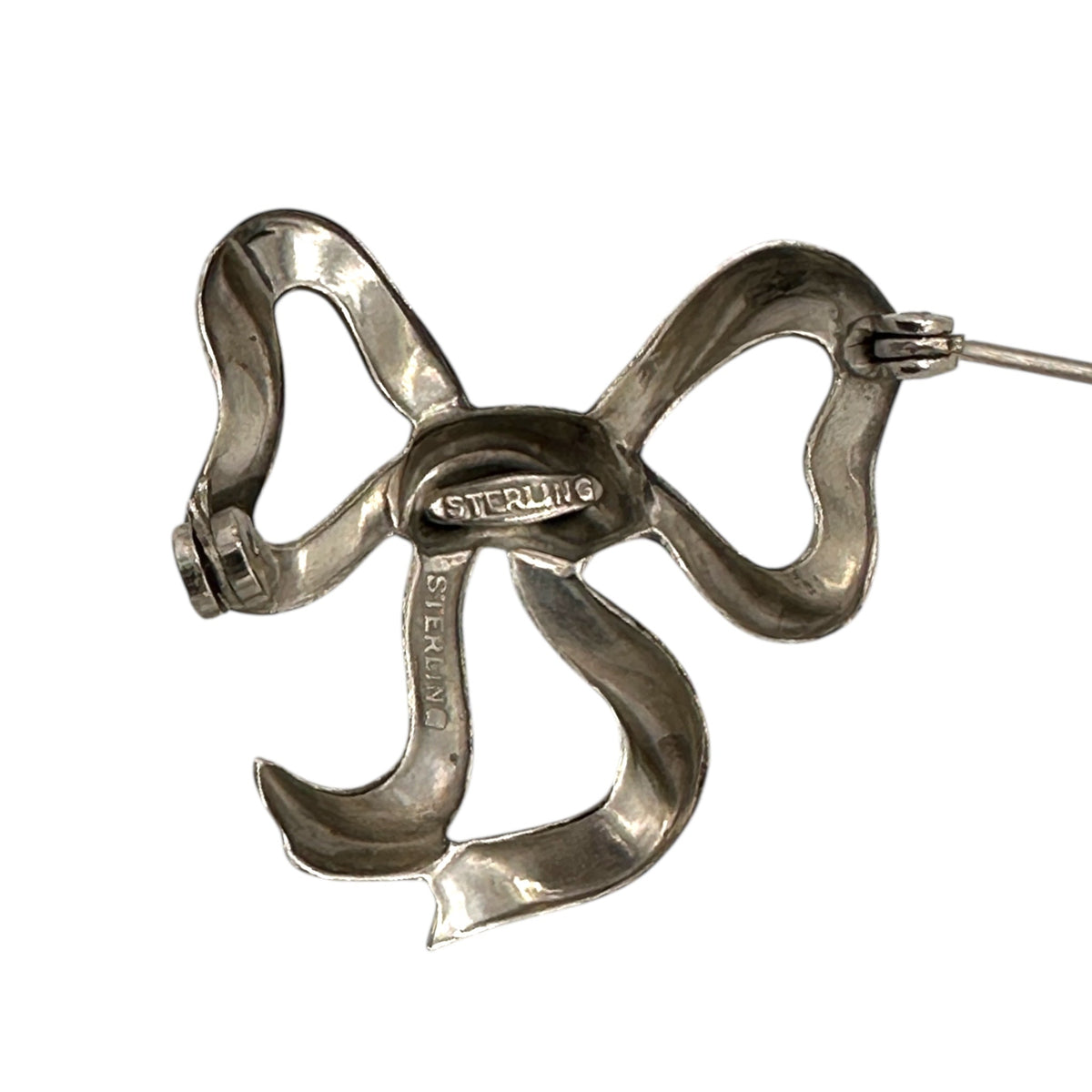 Back view showing Sterling Stamp of Vintage sterling silver bow brooch with polished ribbon design, photographed on white background.