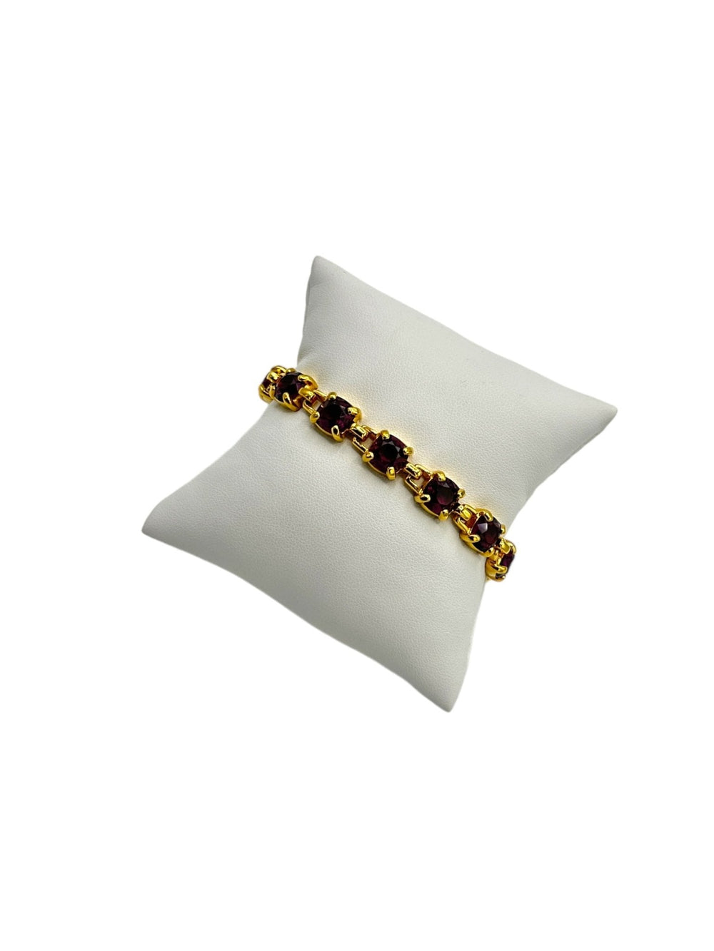 Vintage Swarovski gold-tone tennis bracelet with amethyst purple crystals displayed on a white jewelry pillow.