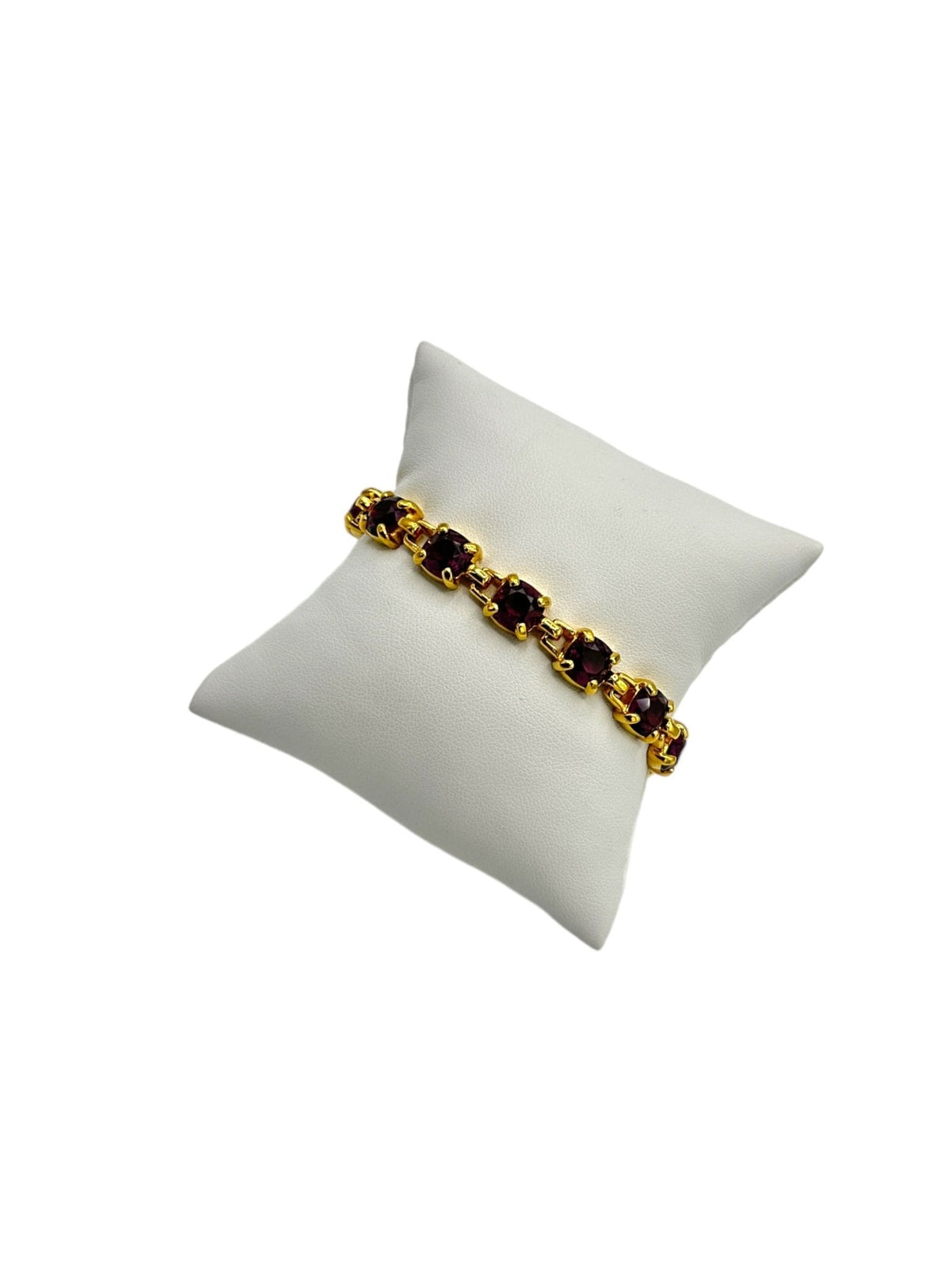 Vintage Swarovski gold-tone tennis bracelet with amethyst purple crystals displayed on a white jewelry pillow.