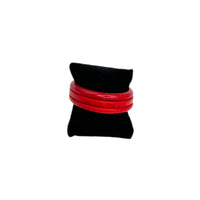Front view of Set of three vintage cherry red Bakelite bangles stacked on black display pillow, glossy Art Deco style.