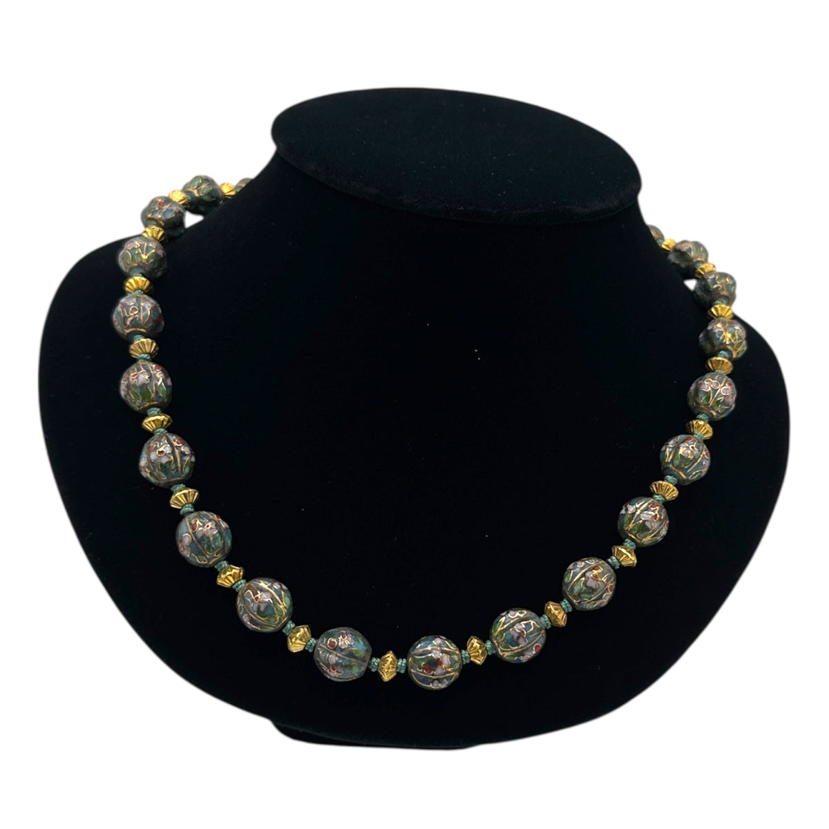 Close up view of Vintage green and gold floral cloisonné bead hand-knotted necklace with scalloped enamel design displayed on black bust.
