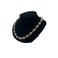 Side view of Vintage green and gold floral cloisonné bead hand-knotted necklace with scalloped enamel design displayed on black bust.