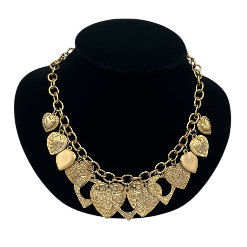 Close up view of Vintage gold heart charm necklace with textured hearts and link chain displayed on black velvet bust.