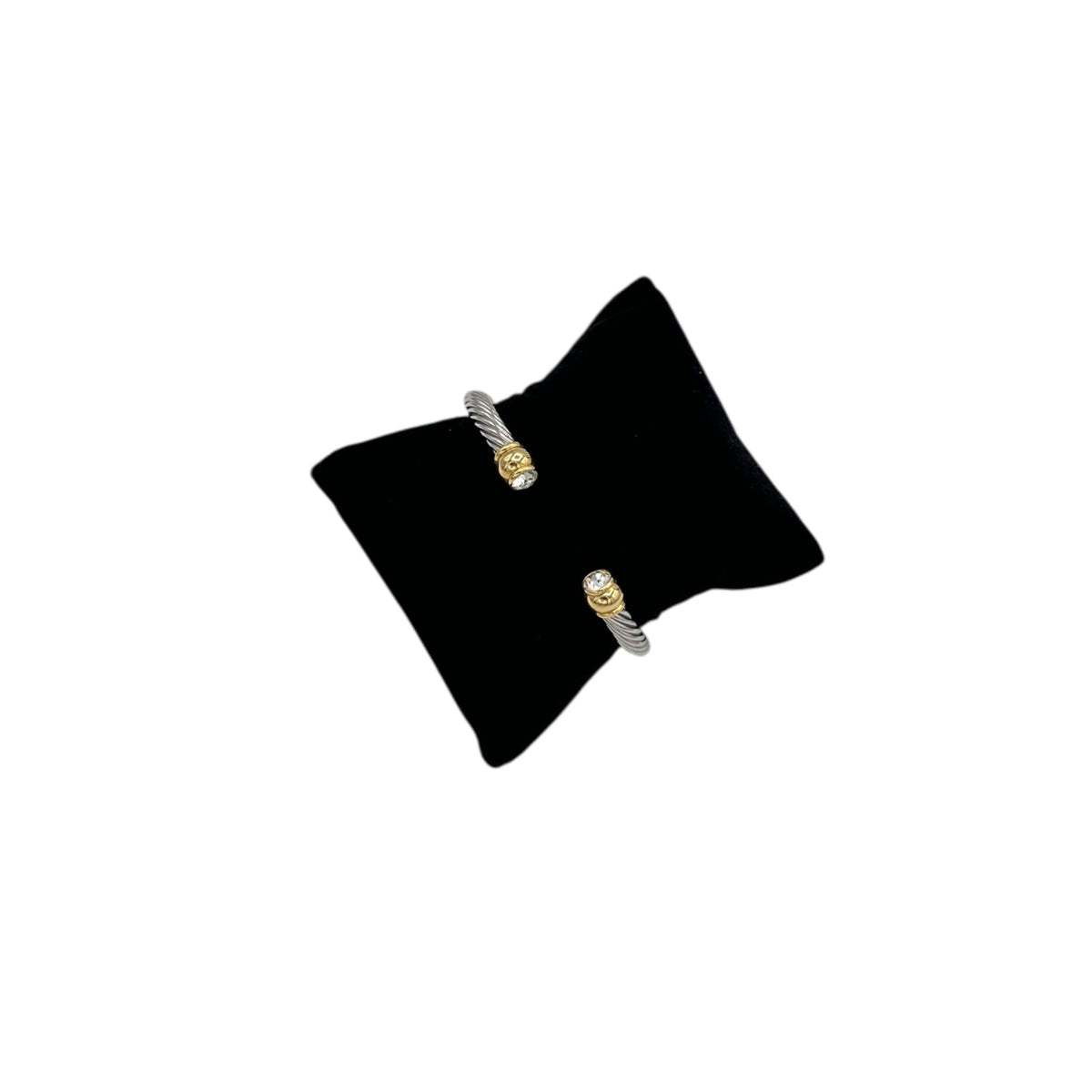 Vintage silver twisted cable open cuff bracelet with gold and rhinestone ends displayed on black pillow white background.